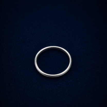 Top-down view of the Glimmer Touch Ring on a dark navy background, showcasing the clean circular silhouette and delicate proportions of the silver band.