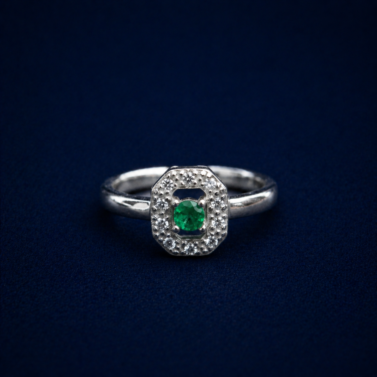 Frontal view of the Evergreen Spark Ring on a dark navy background, displaying the geometric octagonal halo design and the polished silver finish.