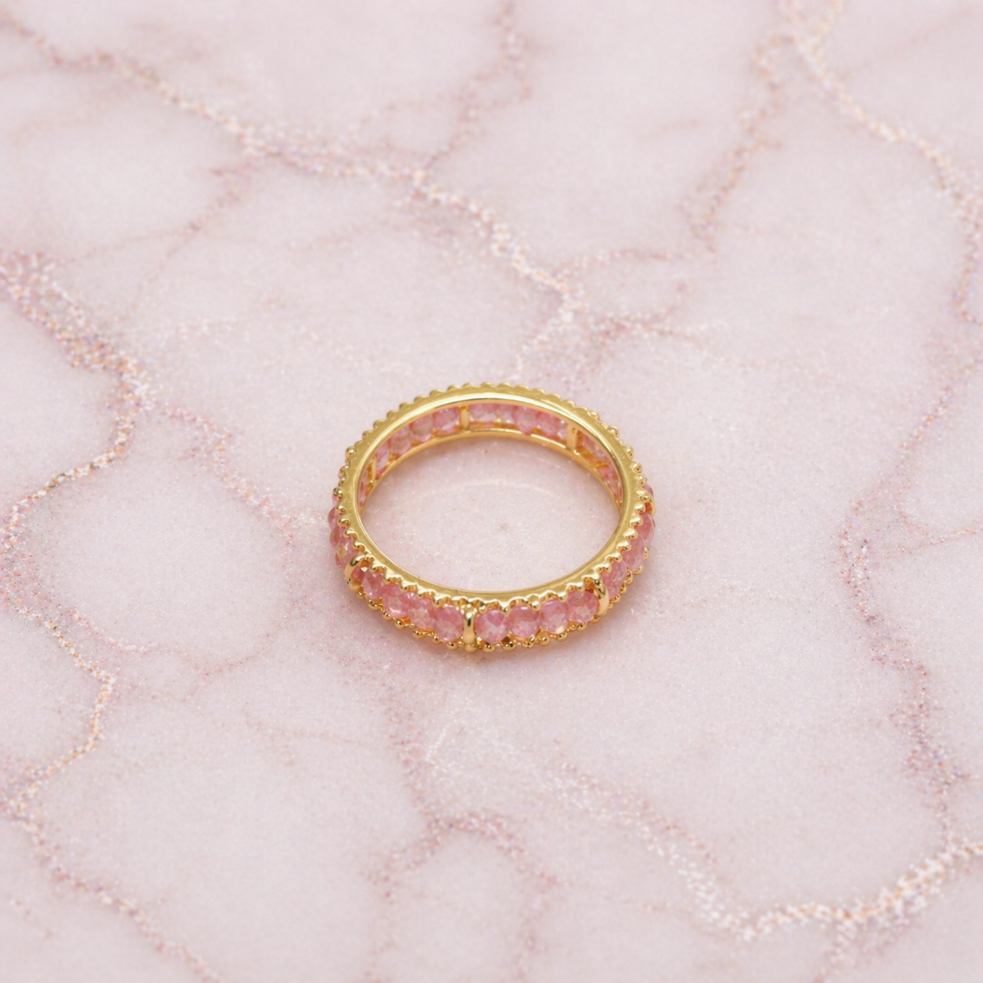 An angled shot of the handcrafted Blush Ball Ring, highlighting the delicate pink tourmaline stones and the polished golden eternity-style setting for a modern, layered look.
