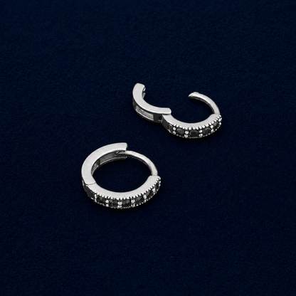 A detailed technical shot of the Eclipse mini hoops showcasing the secure click-to-close hinge mechanism and the  diameter profile, highlighting the textured silver border around the black pavé stones.