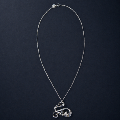 Full studio shot of the Graceful Flow Necklace on a dark navy background, showcasing the fluid, wavy silver pendant and the long, polished sterling silver chain.