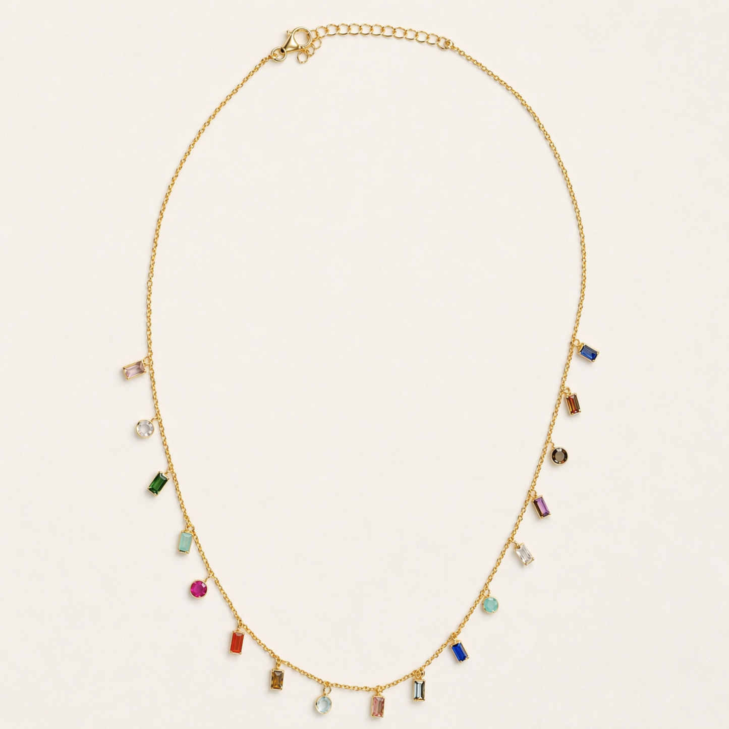 Full studio shot of the A Celebration of Color necklace on a cream background, showcasing the vibrant pattern of garnet, amethyst, citrine, and other gemstones on a delicate gold chain.