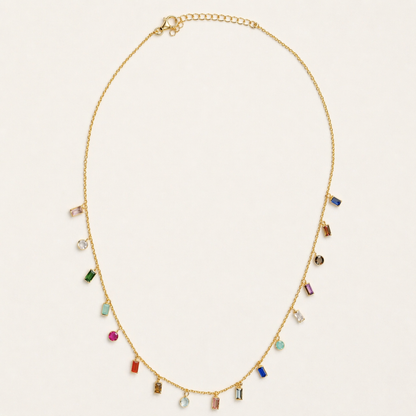 Full studio shot of the A Celebration of Color necklace on a cream background, showcasing the vibrant pattern of garnet, amethyst, citrine, and other gemstones on a delicate gold chain.