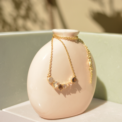 Detailed close-up of the Soft Harmony necklace highlighting the six uniquely shaped stones, including iridescent labradorite and soft peach morganite, set in polished gold.