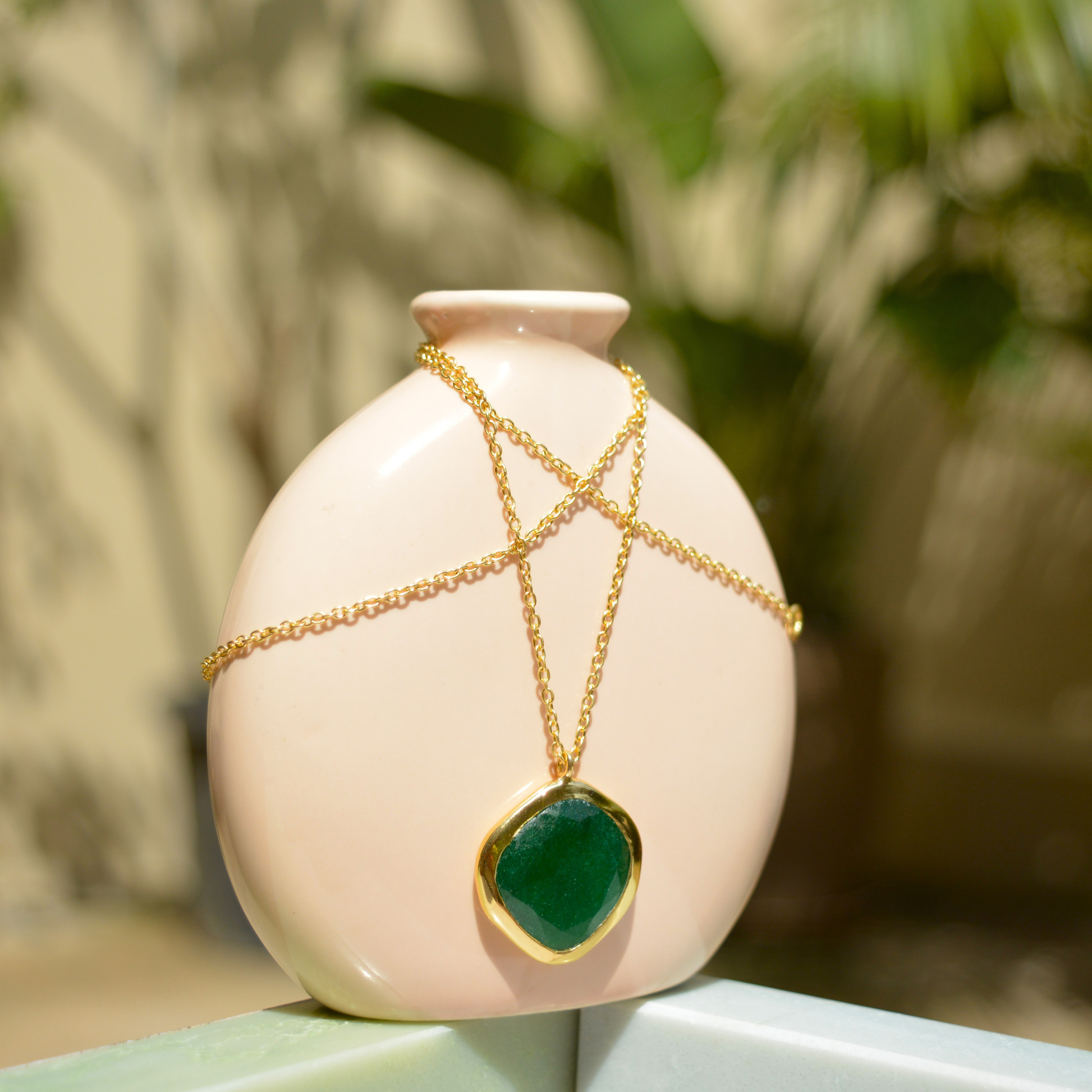 A handcrafted 18kt gold plated Natural Pop necklace featuring an organic square green onyx stone, elegantly draped over a minimal beige ceramic vase.