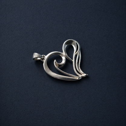 Flat lay view of the A Little Love Pendant on a dark textured background, highlighting the polished rhodium-plated finish and the elegant minimal wired heart silhouette.