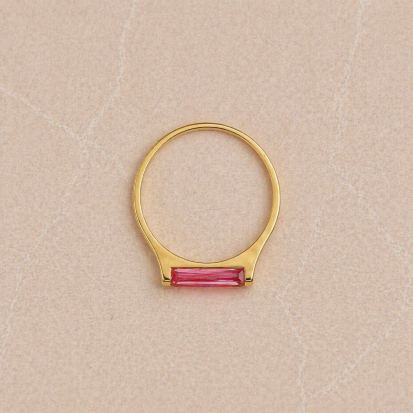 Overhead view of the Blush Glow Ring on a neutral textured surface, highlighting the perfect circular silhouette of the 18kt gold plated 925 sterling silver band and the rectangular pink jade.