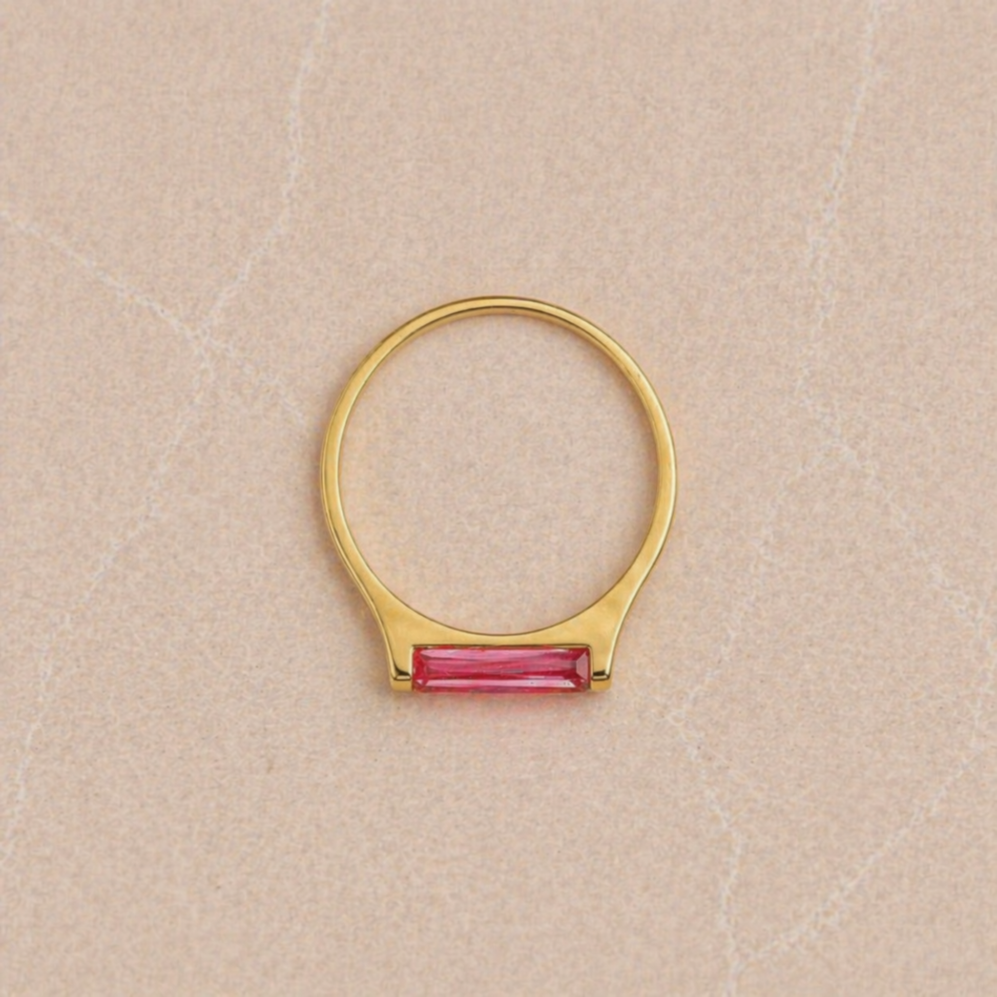 Overhead view of the Blush Glow Ring on a neutral textured surface, highlighting the perfect circular silhouette of the 18kt gold plated 925 sterling silver band and the rectangular pink jade.