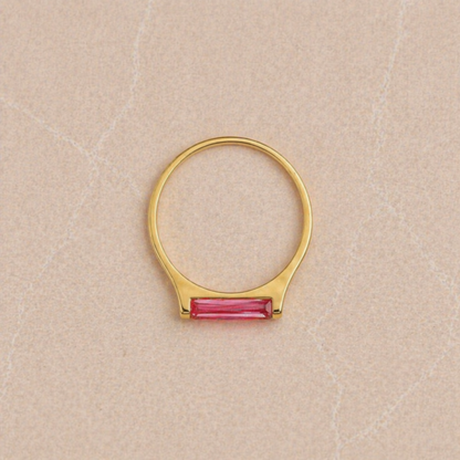 Overhead view of the Blush Glow Ring on a neutral textured surface, highlighting the perfect circular silhouette of the 18kt gold plated 925 sterling silver band and the rectangular pink jade.