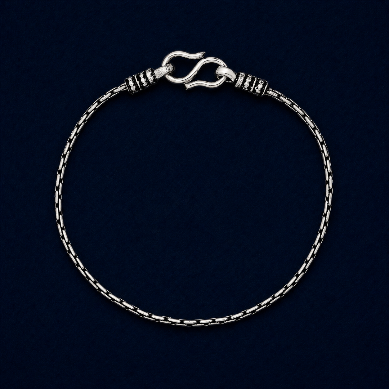 A full studio shot of the handcrafted Rhythm Bar anklet in 925 sterling silver, showcasing the modern brick-style structured links and secure S-hook clasp on a dark navy background.