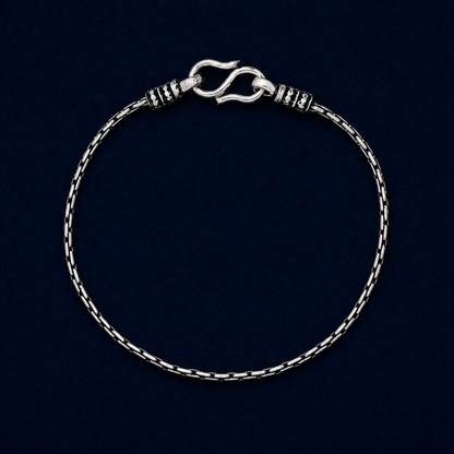 A full studio shot of the handcrafted Rhythm Bar anklet in 925 sterling silver, showcasing the modern brick-style structured links and secure S-hook clasp on a dark navy background.