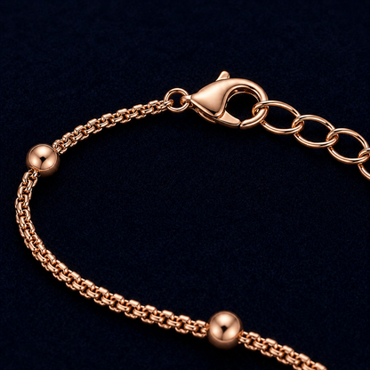 A close-up detail shot of the Subtle Circles bracelet highlighting the high-polish rose gold finish, the textured link chain, and the secure lobster clasp with an adjustable extension chain.