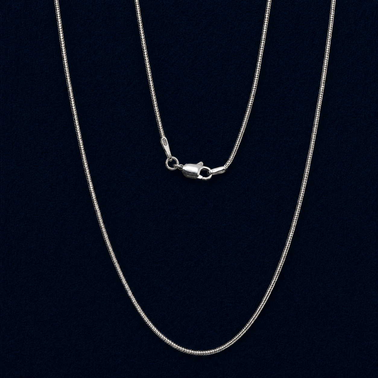 Macro view of a handcrafted 925 sterling silver snake chain necklace, featuring a high-shine lobster clasp and clear 925 authenticity hallmark against a dark navy background.