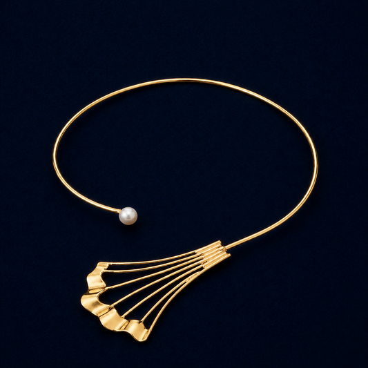 Studio shot of the handcrafted Soft Glow choker in gold plated brass, featuring a minimalist open-neck silhouette with a fan-shaped architectural element and a single luminous white pearl.