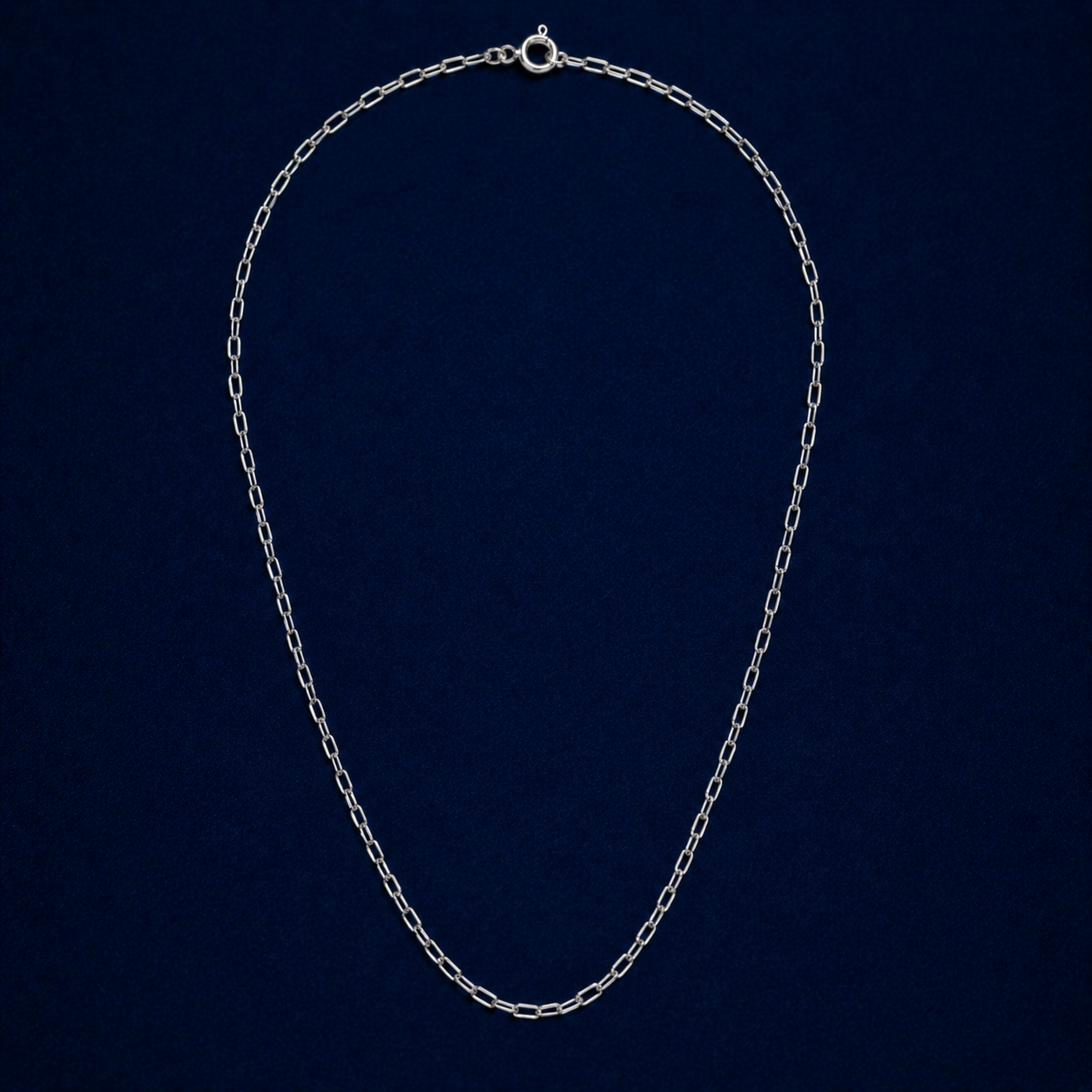 A full studio shot of the handcrafted Subtle Minimal Edge necklace in 925 sterling silver, featuring a modern elongated paperclip link design on a dark navy background.