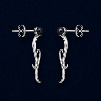 A technical studio shot of the Symphony earrings highlighting the wavy rhodium-plated drops, the integrated blue water pearl studs, and the secure pushback closure mechanism.