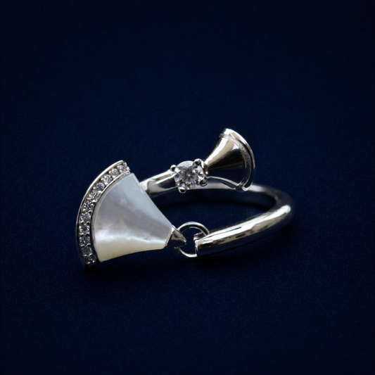 An angled perspective of the handcrafted 925 sterling silver Twilight Curve Ring, featuring a fan-shaped mother of pearl inlay and brilliant-cut CZ accents on an open adjustable band.