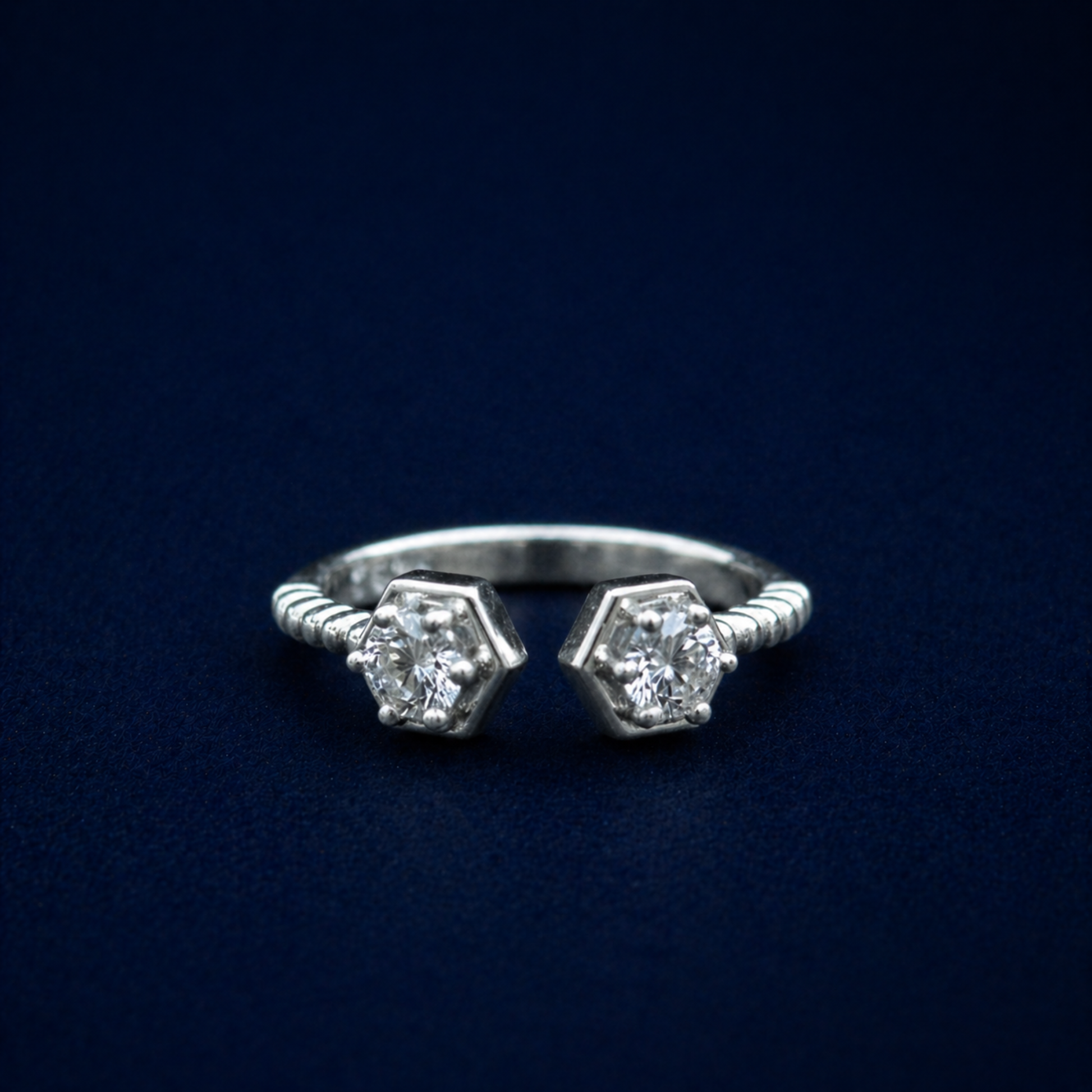 Frontal shot of the A Little Spark Ring showcasing two sparkling hexagonal-cut cubic zirconia stones on an open-front sterling silver band with a modern ribbed texture.