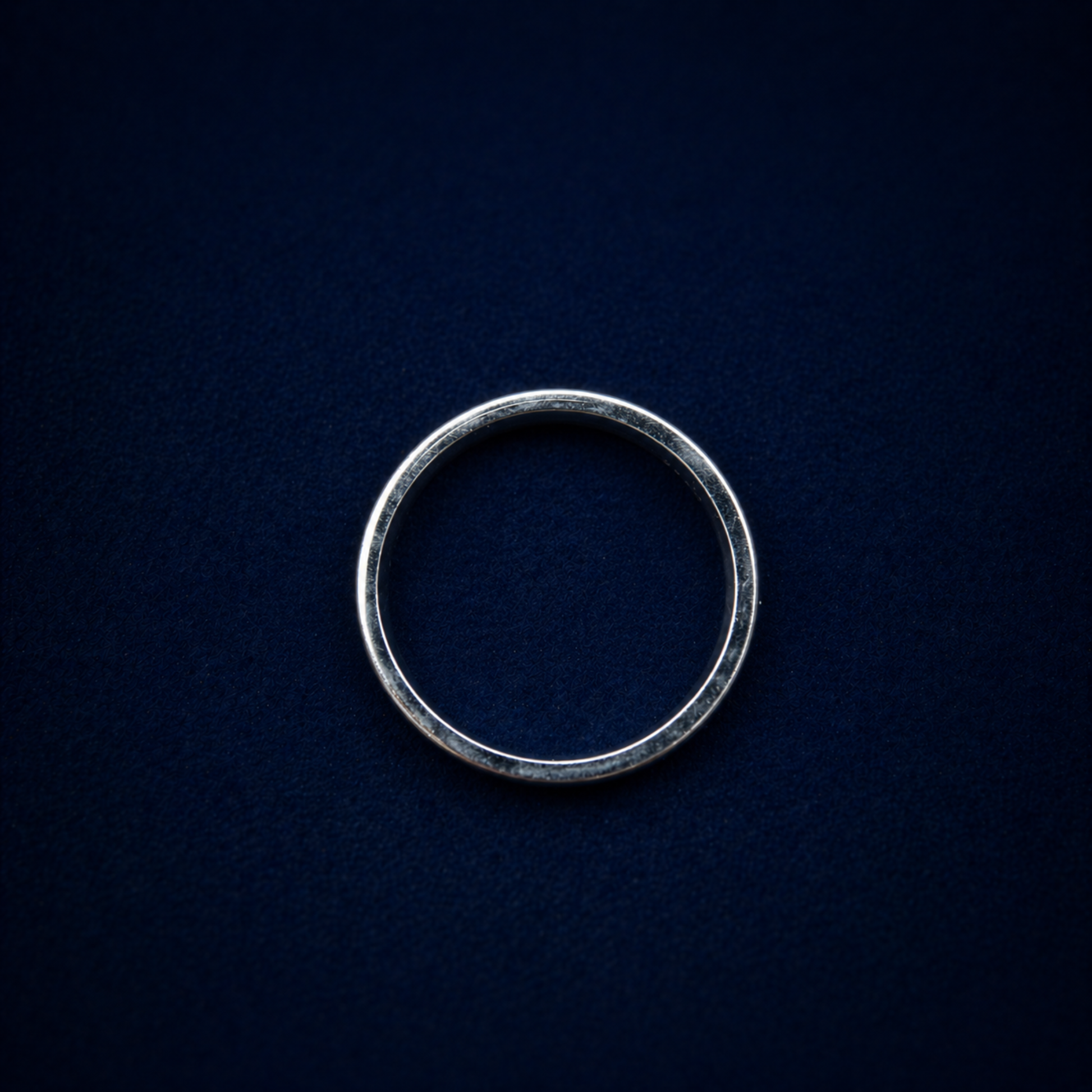 A top-down view of the handcrafted Urban Lines Ring on a dark navy background, showcasing the perfect circular silhouette of the 925 sterling silver band.