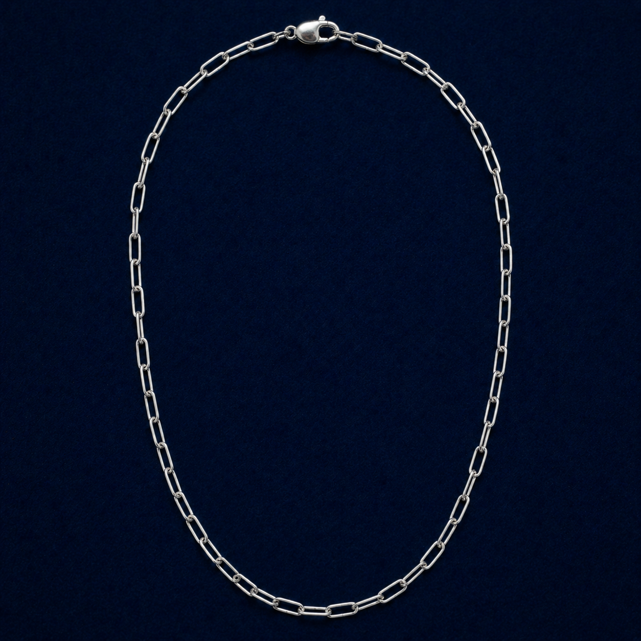 A full studio shot of the handcrafted Urban Paperclip Chain necklace in 925 sterling silver, featuring a sleek elongated link design on a dark navy background.