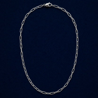 A full studio shot of the handcrafted Urban Paperclip Chain necklace in 925 sterling silver, featuring a sleek elongated link design on a dark navy background.