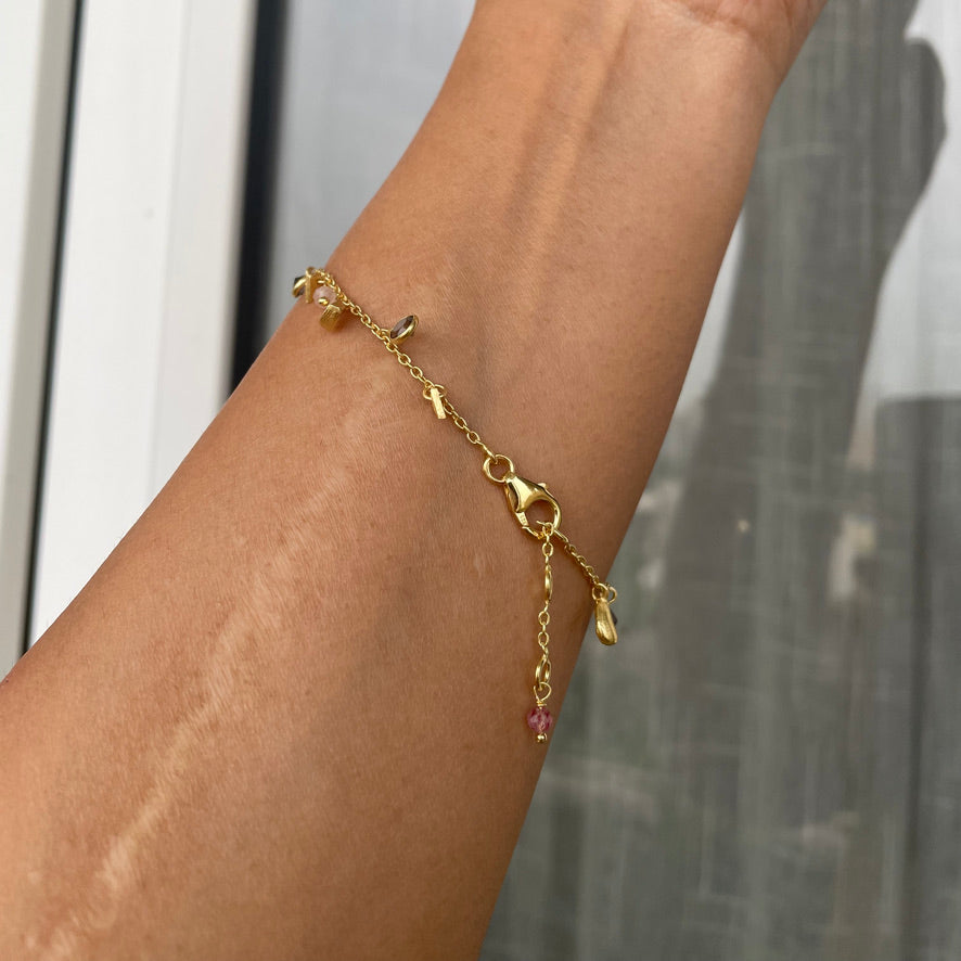 A close-up of a wrist wearing the dainty charm bracelet, highlighting the elegant pairing of natural stones and gold-plated silver.