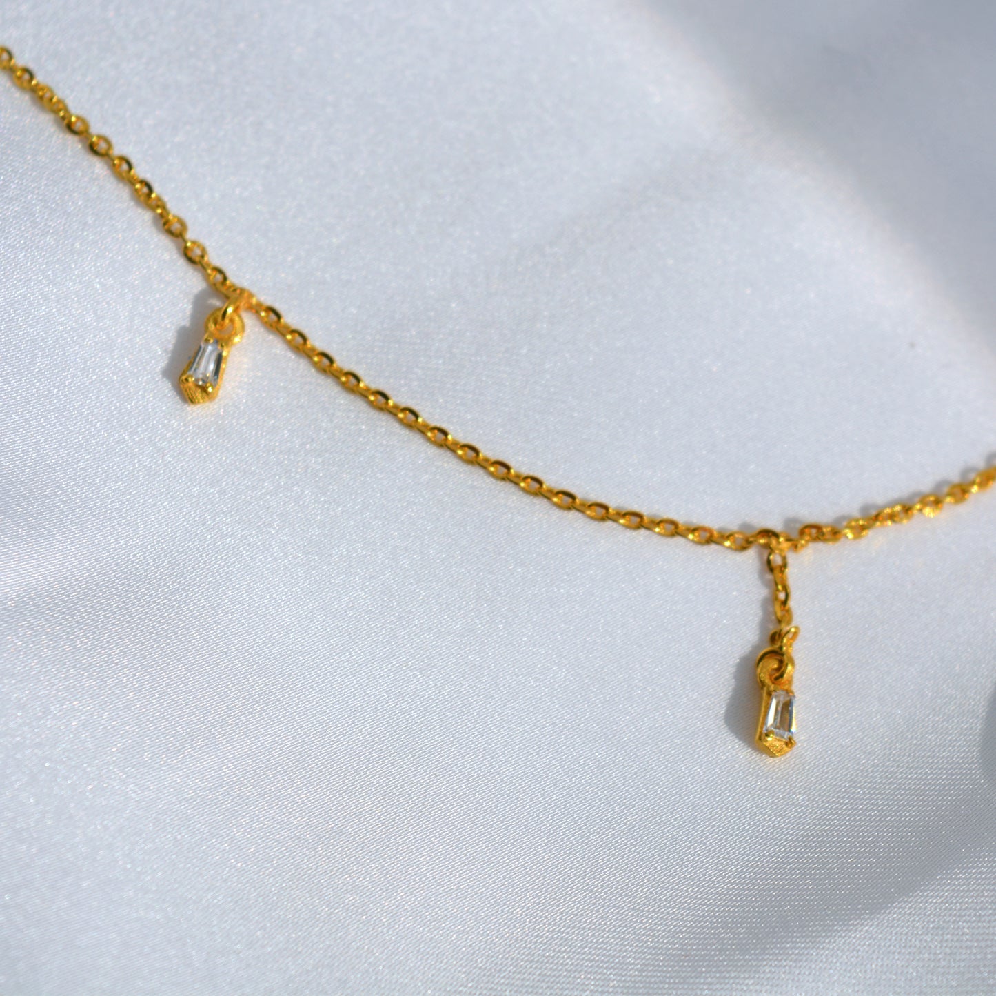 A studio shot of a minimalist gold-toned necklace with small, evenly placed stations, emphasizing its high-shine finish and contemporary style.