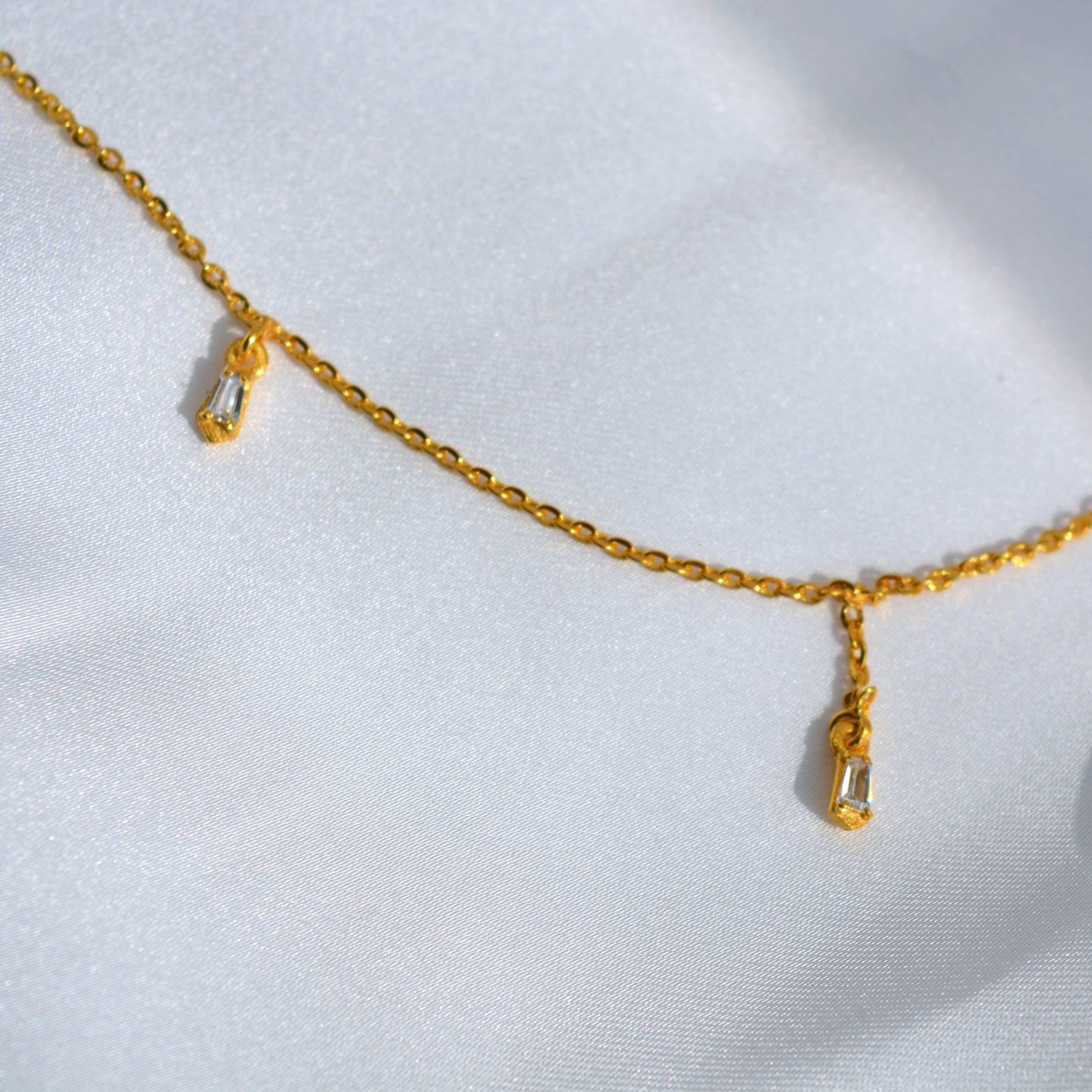 A studio shot of a minimalist gold-toned necklace with small, evenly placed stations, emphasizing its high-shine finish and contemporary style.