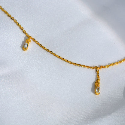 A studio shot of a minimalist gold-toned necklace with small, evenly placed stations, emphasizing its high-shine finish and contemporary style.