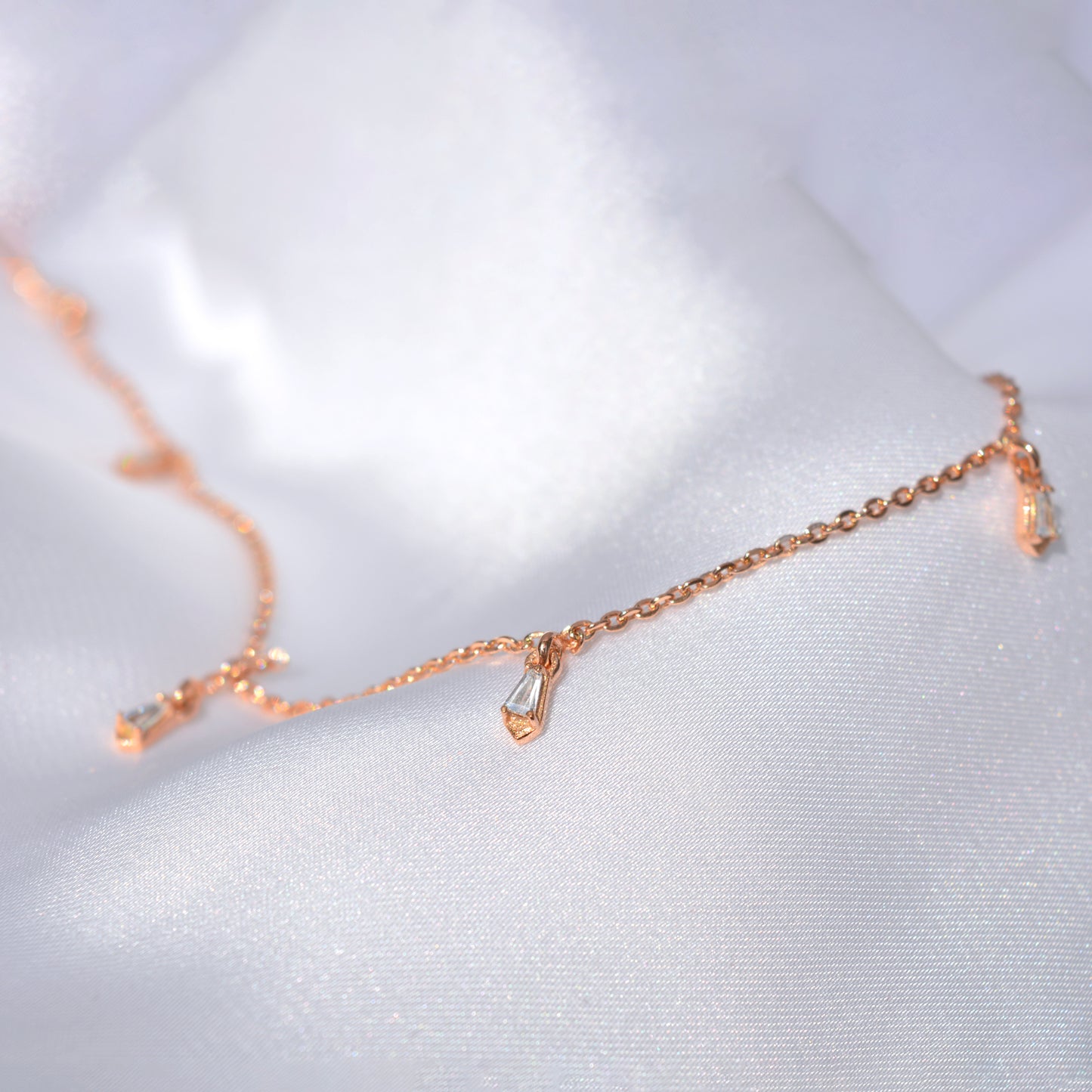 A stylish, airy rose gold necklace laid out on a soft, textured surface, emphasizing its light and versatile design perfect for everyday luxury.