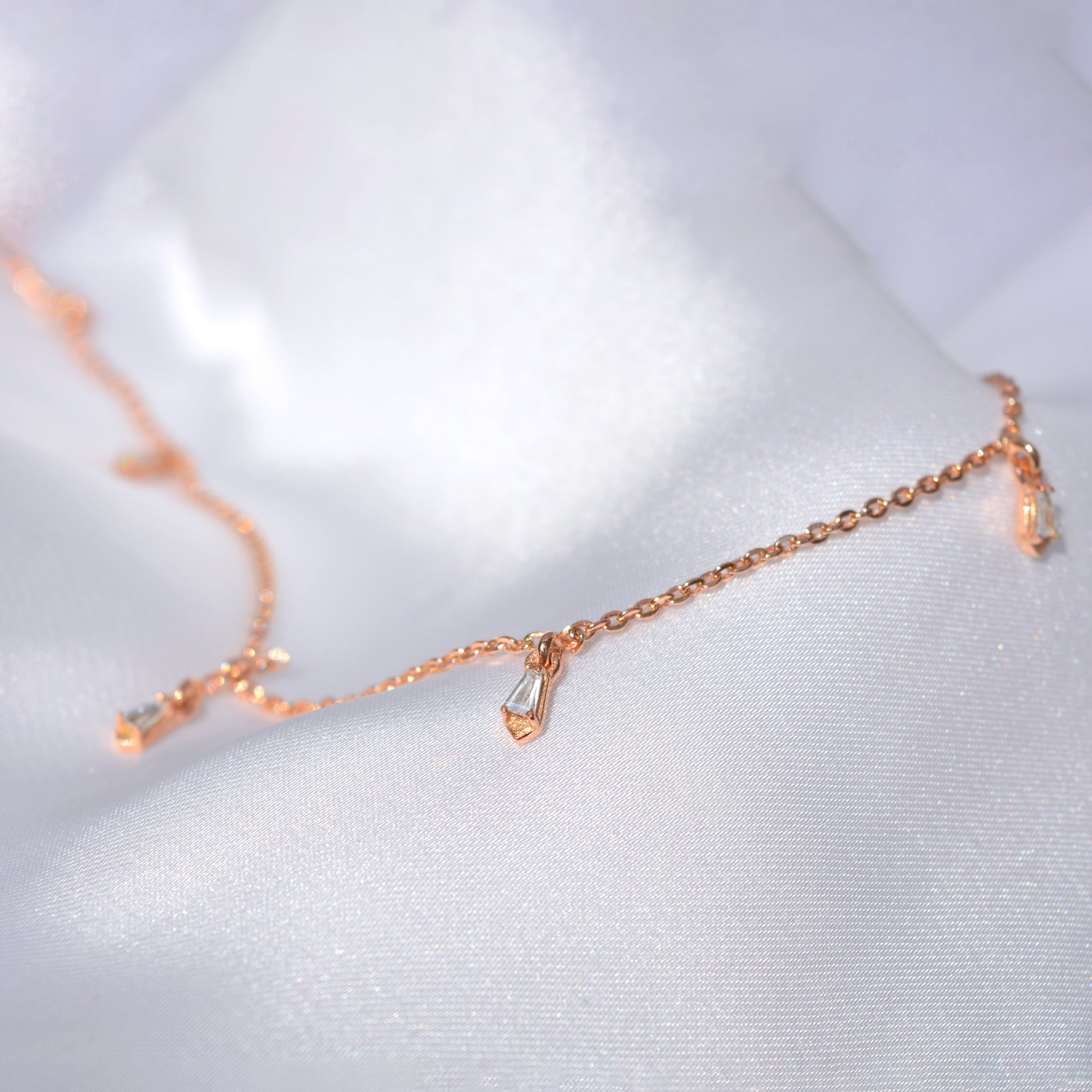 A stylish, airy rose gold necklace laid out on a soft, textured surface, emphasizing its light and versatile design perfect for everyday luxury.