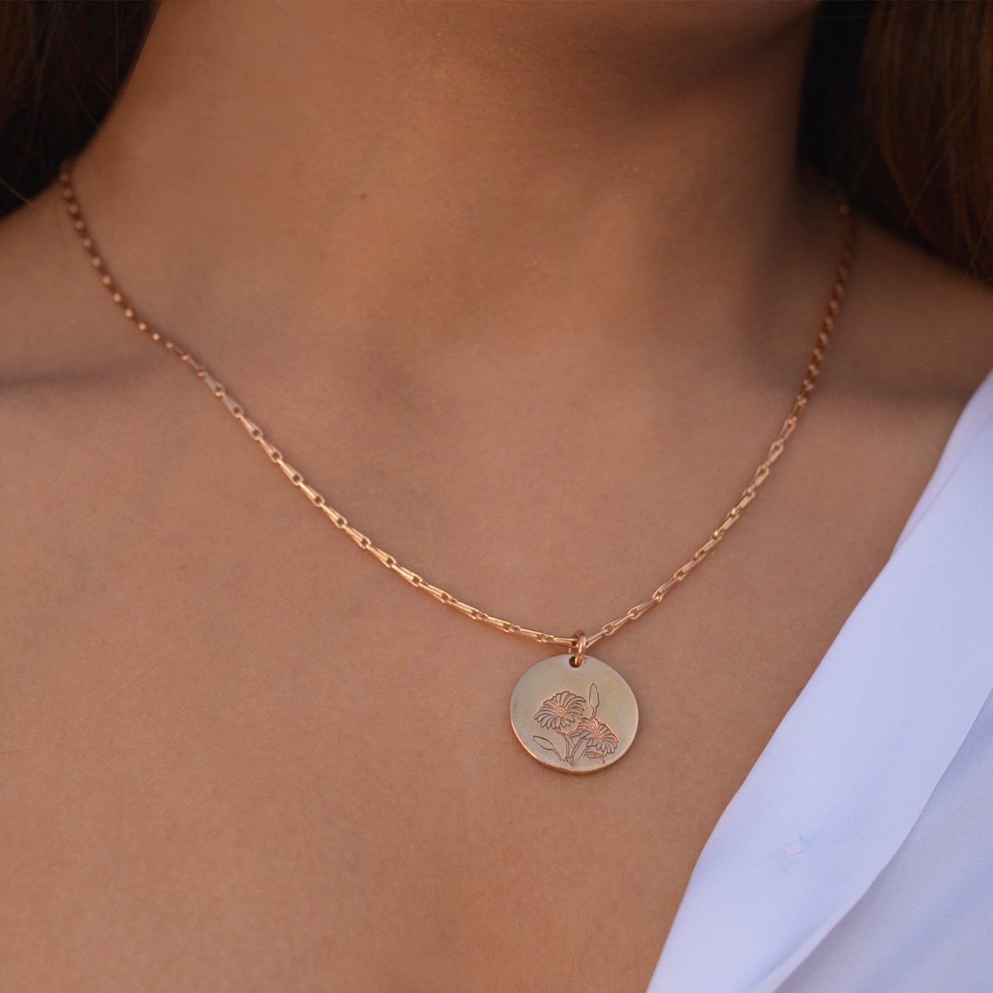 A model wearing the Daisy Medallion Necklace styled with a white button-down shirt, illustrating a classic, everyday jewelry look.