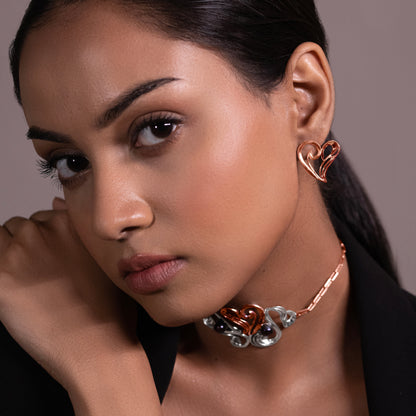 A model showcasing elegant rose gold heart studs handcrafted in 925 sterling silver, featuring a thick micron plating for long-lasting brilliance.