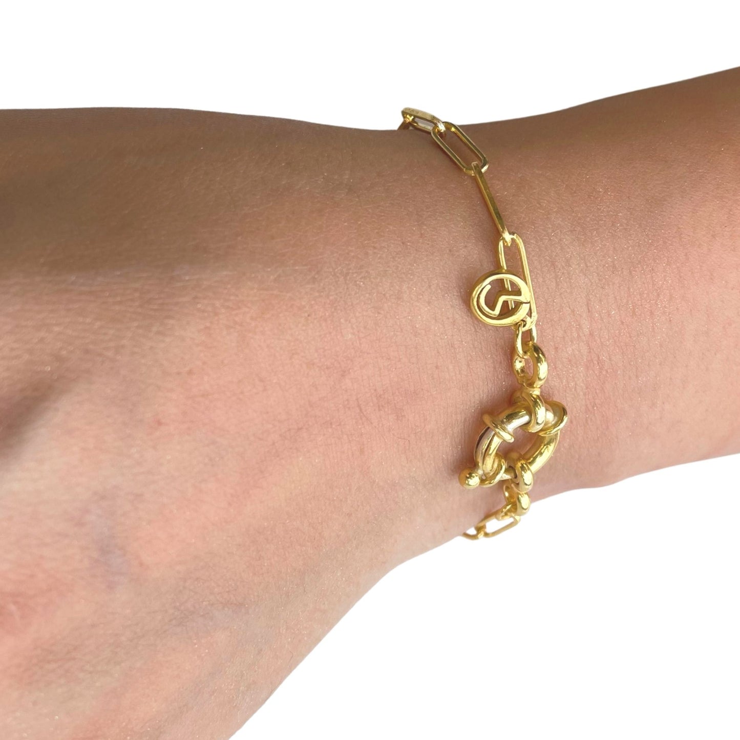 A gold-tone minimalist chain bracelet on a wrist, showcasing the slender profile and modern interlocking link design.
