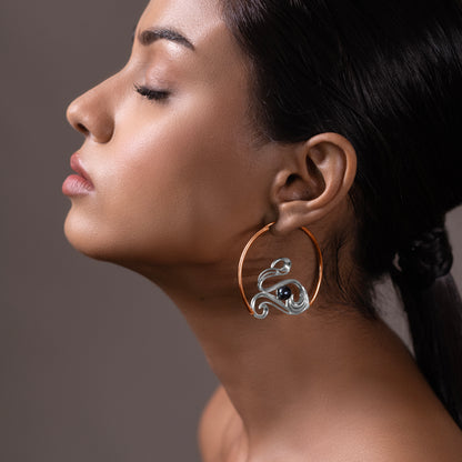 Side profile of a person showcasing oversized sterling silver hoops with an artistic, fluid design reflecting a modern oceanic aesthetic.