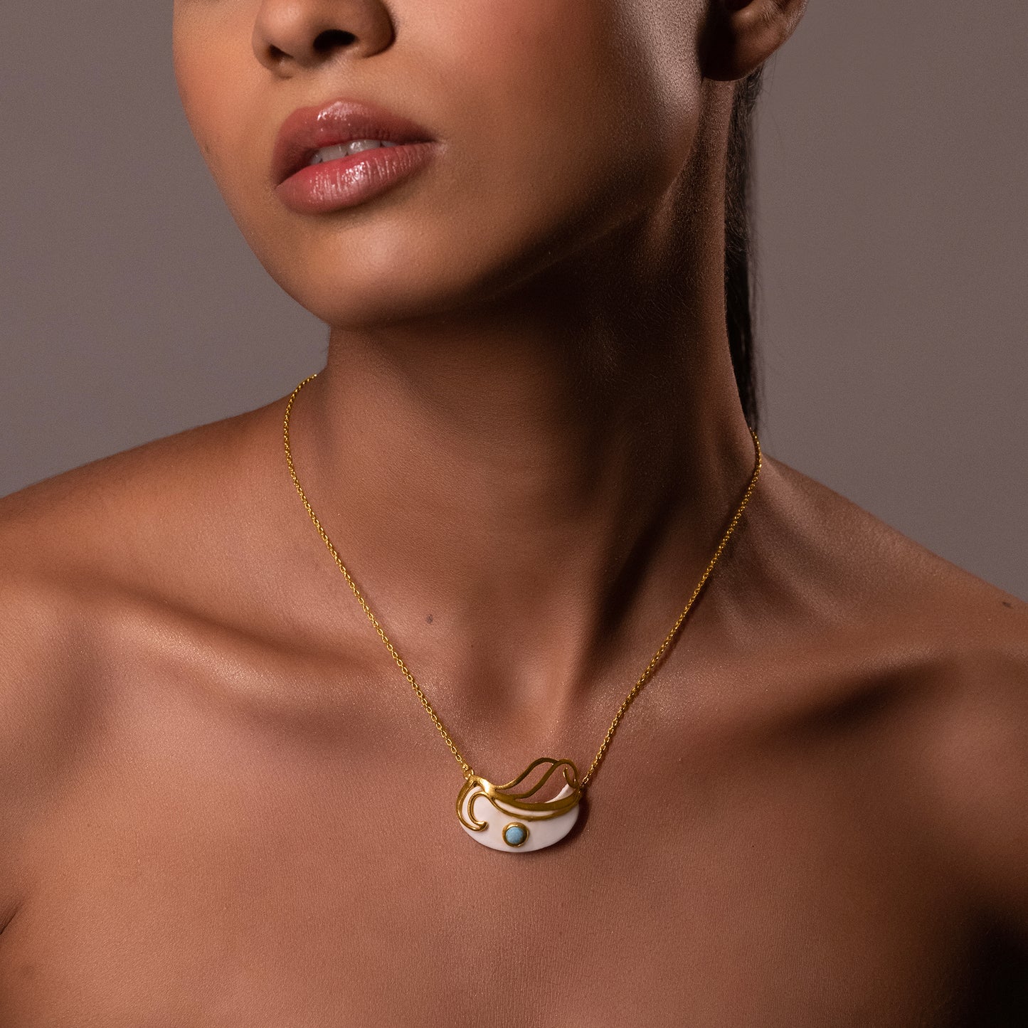 A model featuring the Mystic Turquoise Necklace, emphasizing how the sculptural gold and white pendant sits perfectly on the collarbone.
