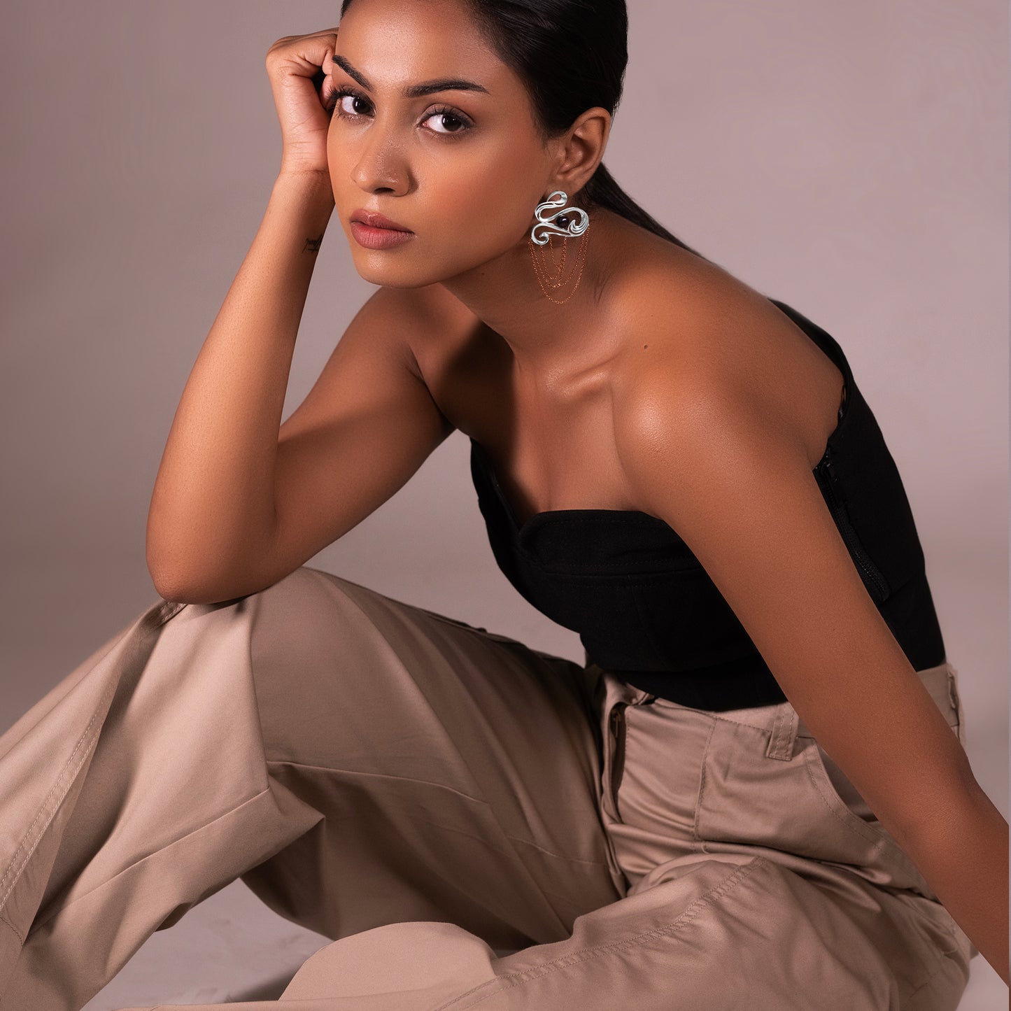 Model wearing handcrafted fine silver chandelier earrings featuring an intricate dual-tone 18k rose gold and platinum plating with whimsical wave-inspired patterns.
