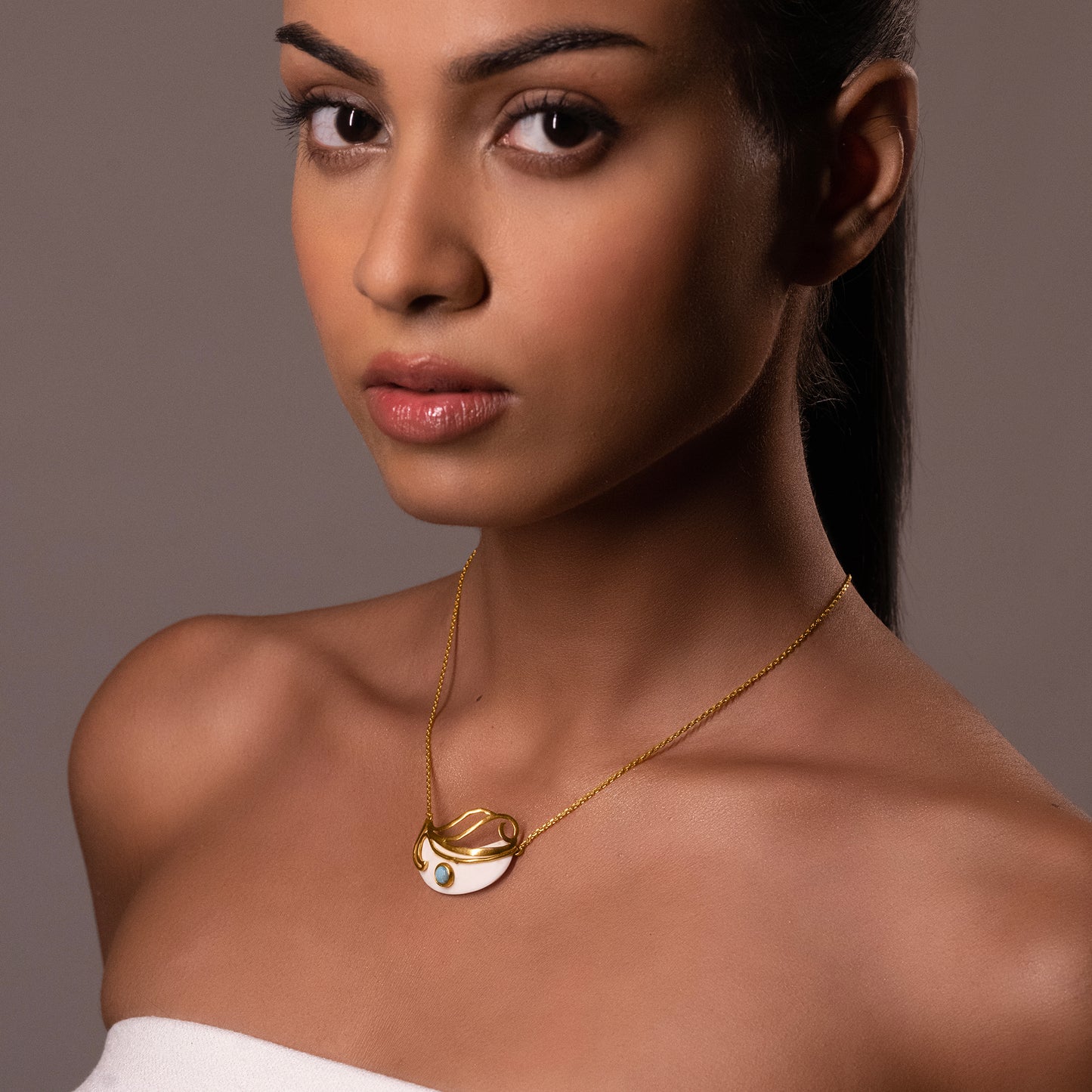 Close-up of a model wearing the Mystic Turquoise Necklace, showcasing the gold-plated statement pendant against her skin.