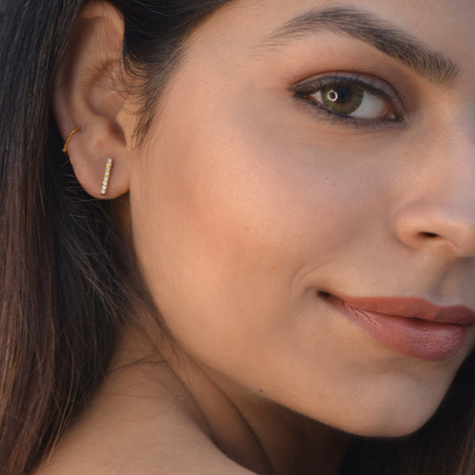 A close-up of a model wearing a sleek, minimalist metallic horizontal bar stud earring that offers a modern and understated look for daily wear.