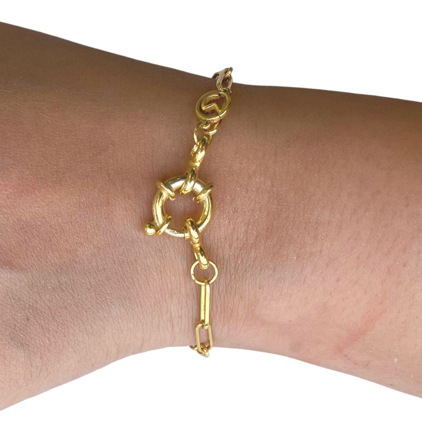 Close-up of a person's wrist wearing a dainty gold link bracelet with a high-shine finish and a circular statement fastener.
