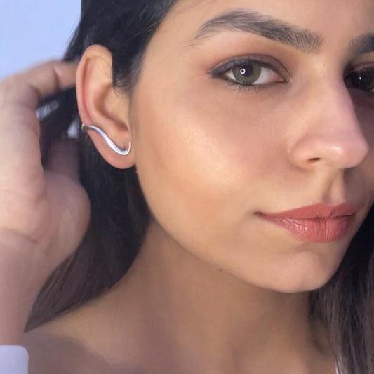 Side profile of a model wearing a silver ear climber, showcasing elegantly drape and follow the ear's contour.