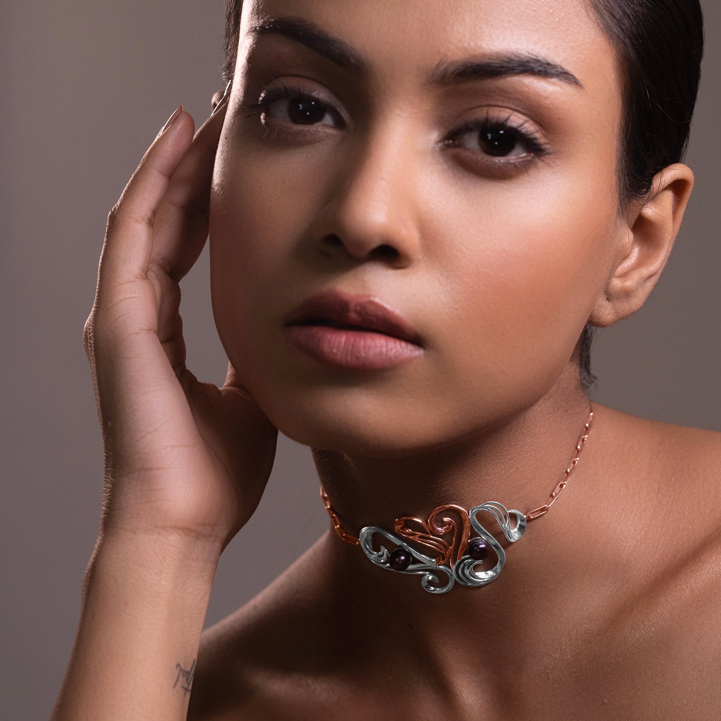 Close-up of a model wearing a sophisticated silver choker necklace featuring a central, sculptural wave-inspired focal point.