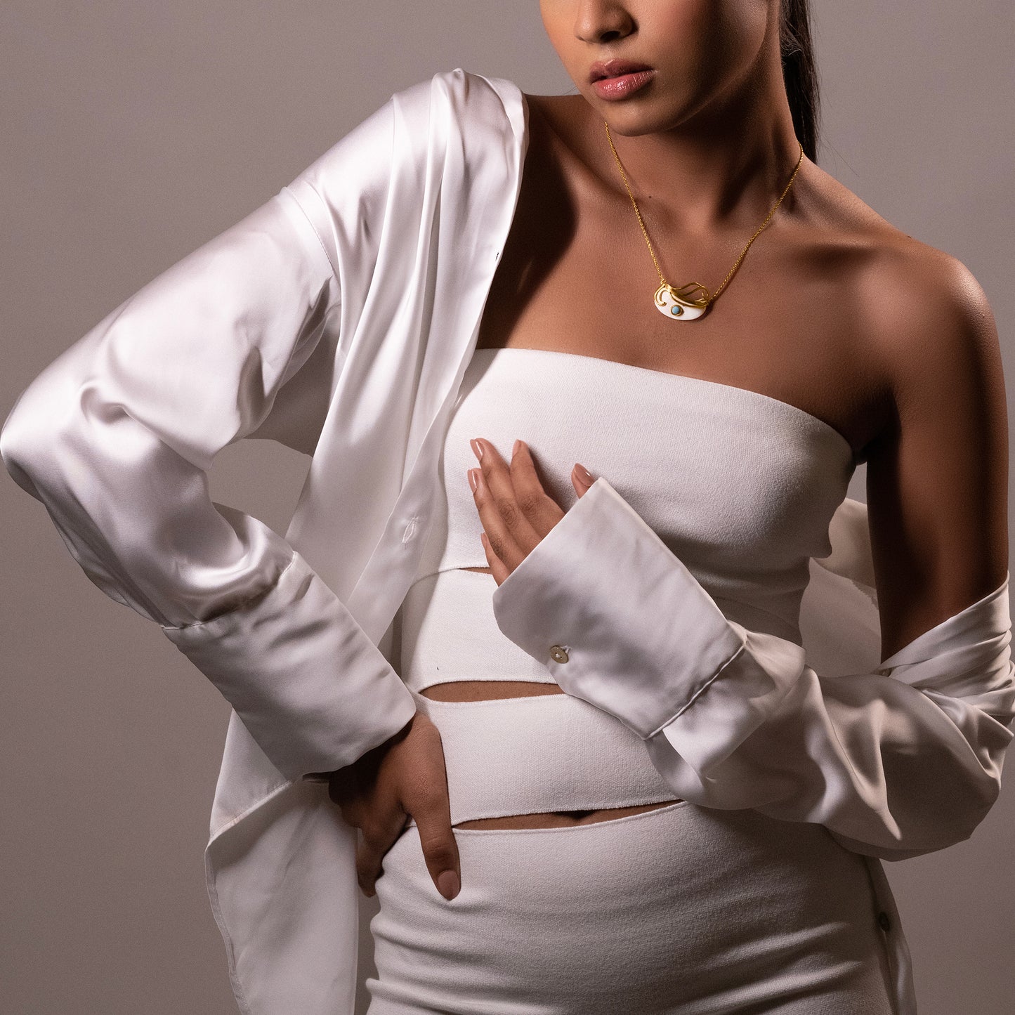 Fashion shot of a model in a white strapless top and silk shirt styled with the Mystic Turquoise Necklace for a luxury look.