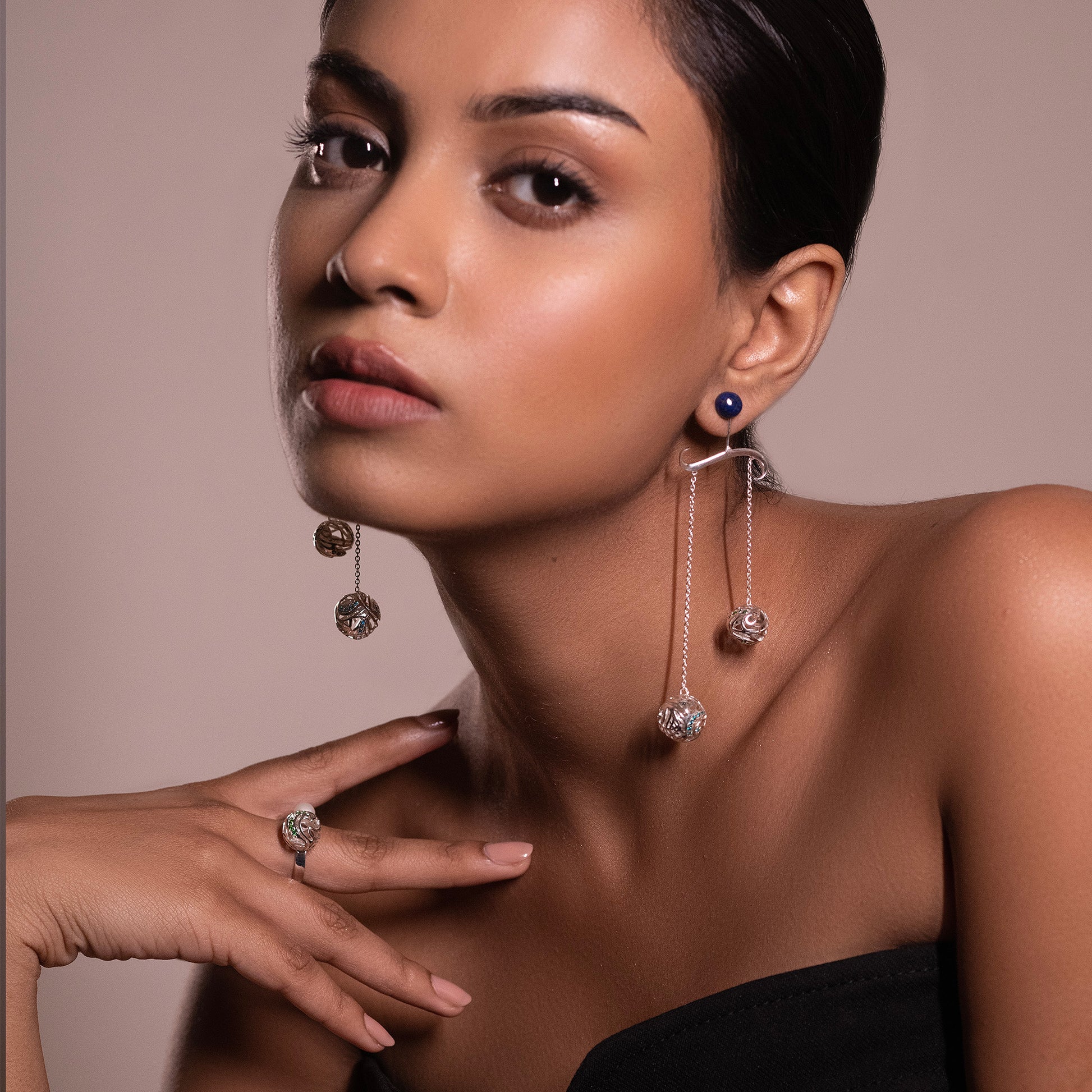Model wearing long silver statement earrings with blue stone accents, showcasing a tiered bohemian drop design.