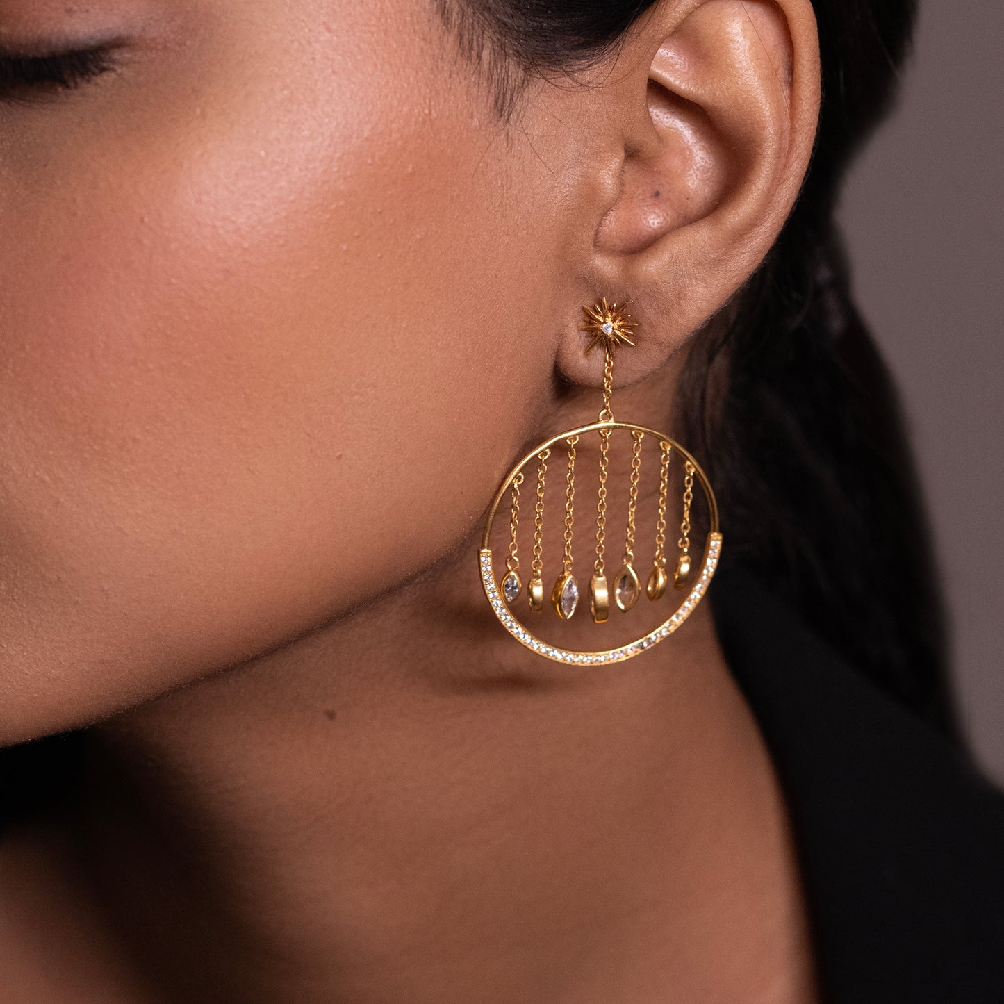 Close-up of a glamorous 18k gold-plated chandelier earring featuring cascading celestial-inspired charms and brilliant zirconia stones.