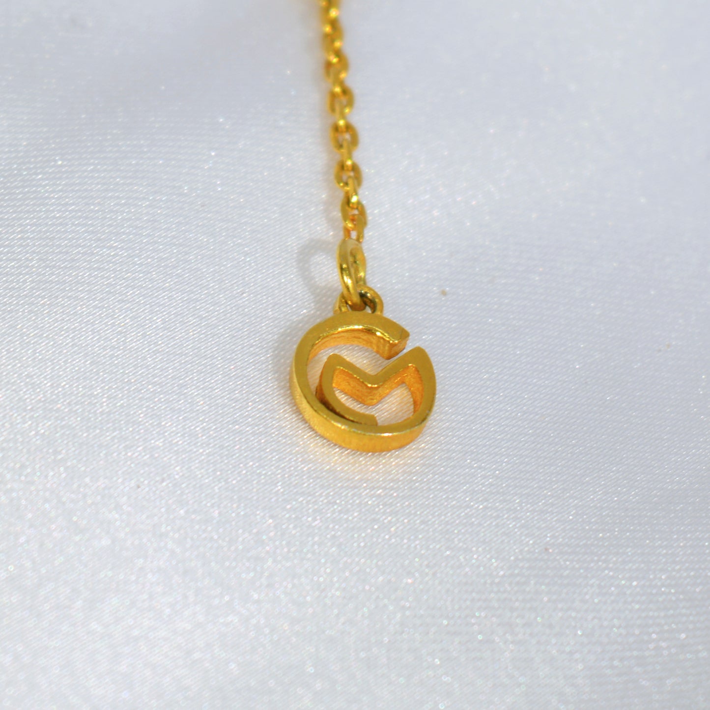 Close-up of a delicate yellow gold-plated necklace, highlighting the refined craftsmanship and brands logo.