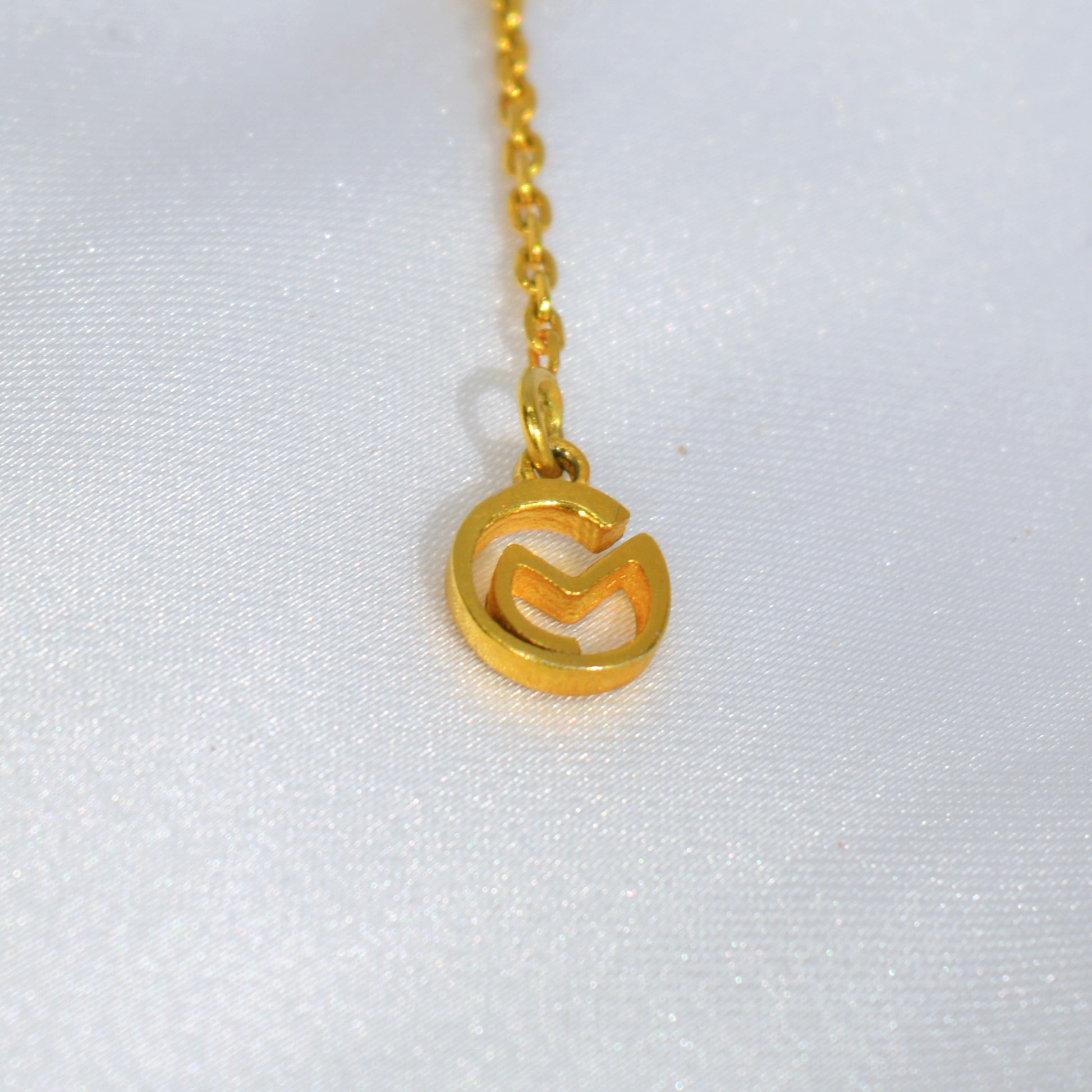 Close-up of a delicate yellow gold-plated necklace, highlighting the refined craftsmanship and brands logo.