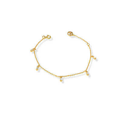 A dainty gold chain bracelet decorated with five dangling, clear baguette-style stone charms, set against a solid white background.