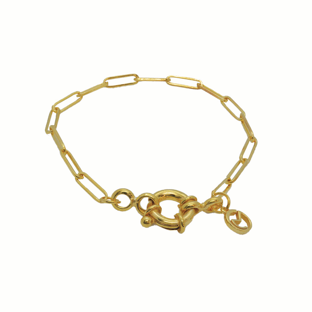 A gold-plated paperclip chain bracelet featuring elongated rectangular links and a prominent decorative oversized spring ring clasp.