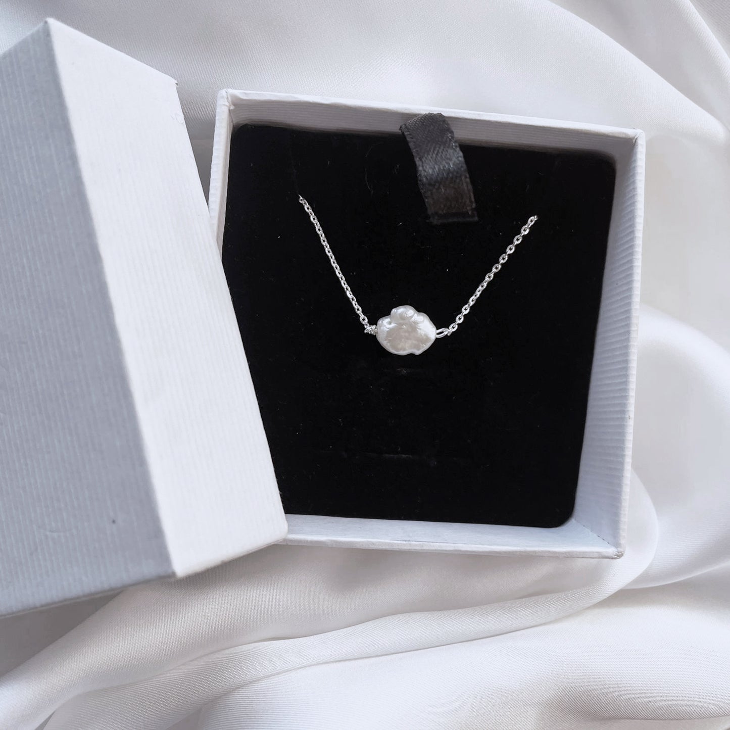 A classic, elegant strand of perfectly rounded, luminous white pearl, highlighting their natural luster and smooth, uniform finish against a clean studio background.